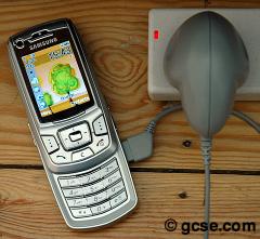 mobile phone plugged in and recharging with a transformer to alter the voltage of the electrical supply